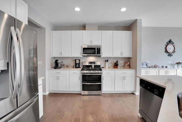 kitchen with tasteful backsplash, light wood-style floors, appliances with stainless steel finishes, and light countertops