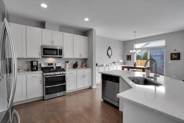 kitchen with a sink, a chandelier, decorative backsplash, white cabinets, and appliances with stainless steel finishes