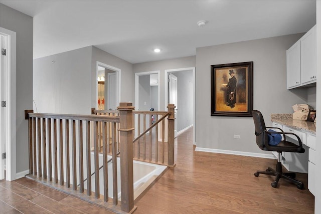 office area featuring wood finished floors, recessed lighting, built in desk, and baseboards
