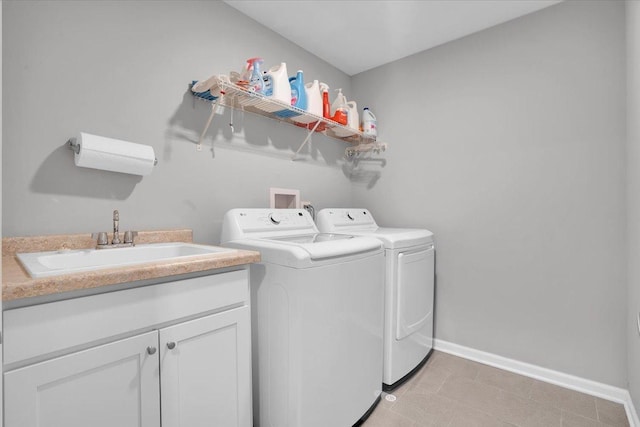 clothes washing area featuring light tile patterned floors, cabinet space, washing machine and clothes dryer, a sink, and baseboards