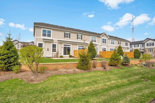 back of house with fence, a lawn, and a residential view