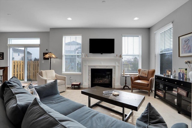carpeted living area featuring baseboards, recessed lighting, a wealth of natural light, and a high end fireplace