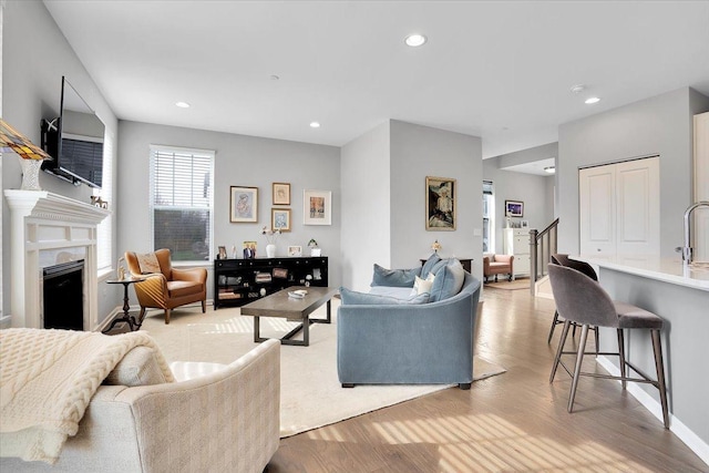 living room featuring a fireplace, recessed lighting, and light wood finished floors
