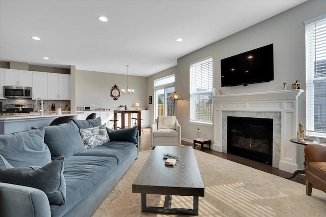 living room with recessed lighting, an inviting chandelier, a wealth of natural light, and a fireplace