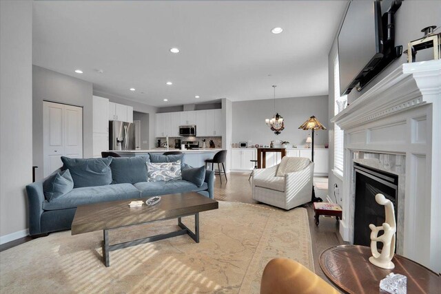 living area with a fireplace, a chandelier, recessed lighting, and light wood finished floors