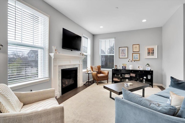 living room with recessed lighting, a premium fireplace, wood finished floors, and baseboards