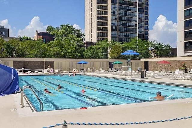 community pool with a patio area and area for grilling