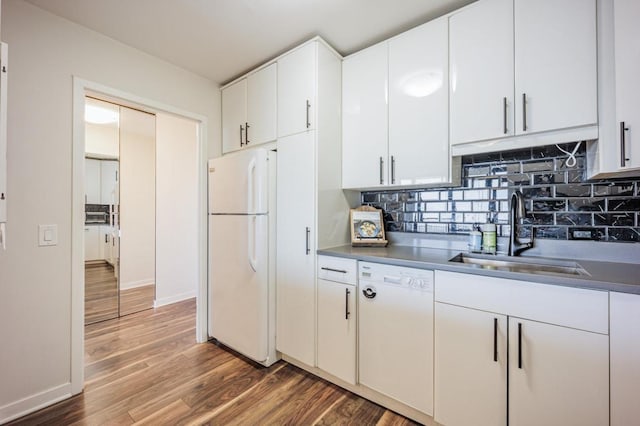 kitchen featuring white cabinets, wood finished floors, a sink, white appliances, and decorative backsplash