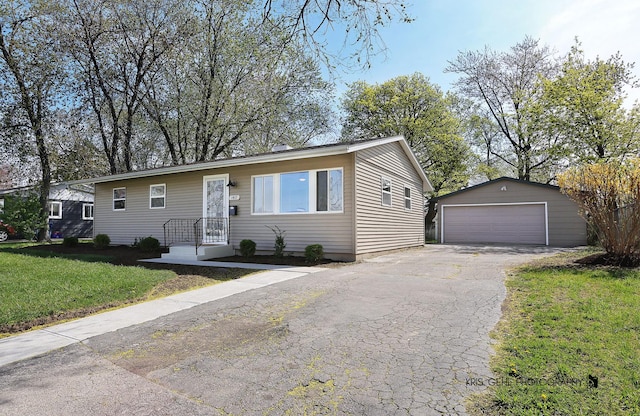 view of front of house featuring a detached garage, an outbuilding, and a front yard