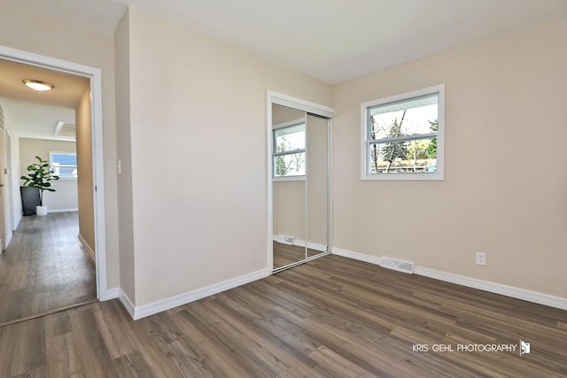 unfurnished bedroom featuring visible vents, baseboards, wood finished floors, and a closet