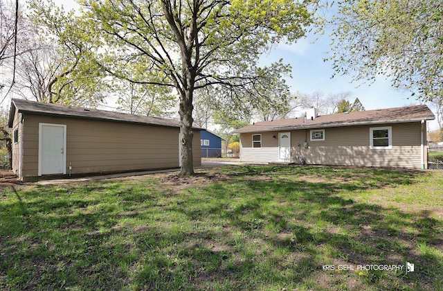back of house featuring an outdoor structure and a yard