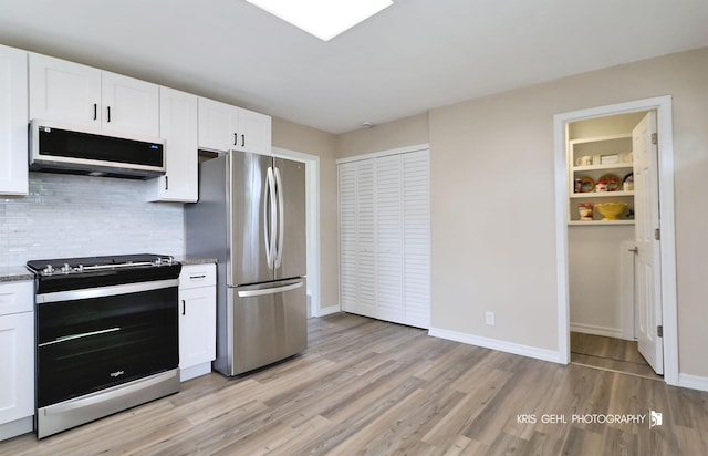 kitchen with tasteful backsplash, baseboards, white cabinets, light wood-style floors, and stainless steel appliances