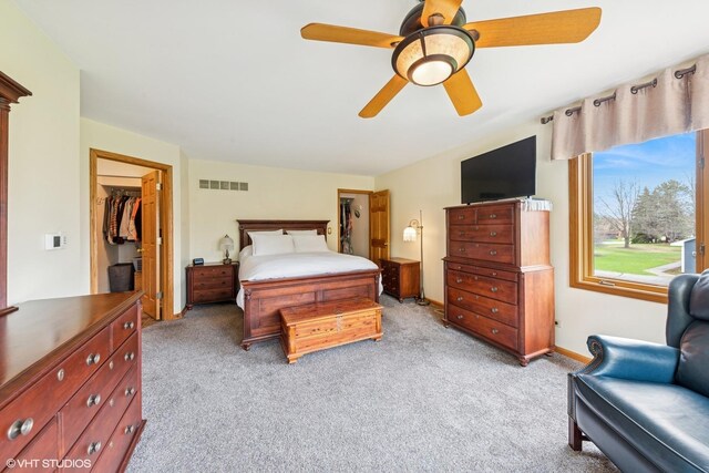 bedroom with a spacious closet, visible vents, a ceiling fan, a closet, and light colored carpet