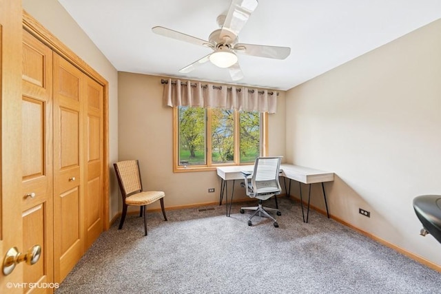 carpeted office space featuring a ceiling fan and baseboards