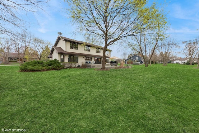 back of property with a lawn and stucco siding