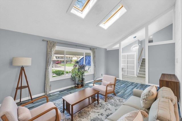 living area featuring lofted ceiling, a skylight, wood finished floors, plenty of natural light, and stairs