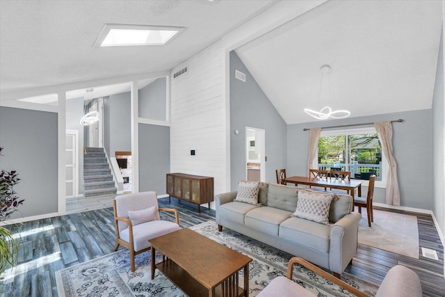 living area featuring a chandelier, wood finished floors, high vaulted ceiling, baseboards, and stairway