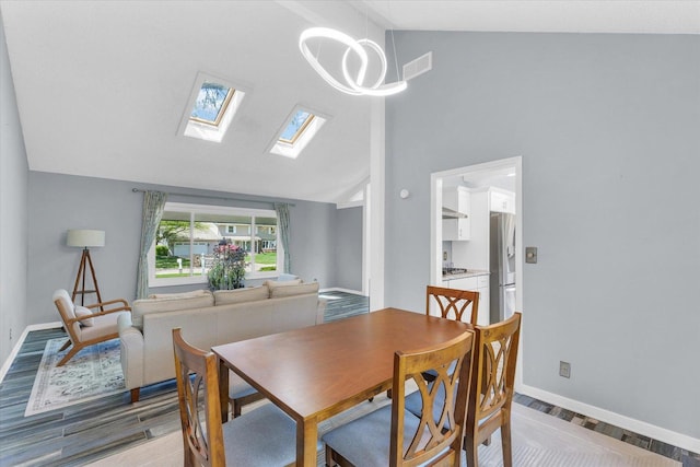 dining space with high vaulted ceiling, light wood-style floors, baseboards, a skylight, and a chandelier