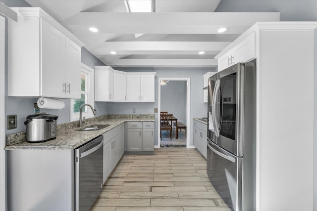 kitchen featuring appliances with stainless steel finishes, a sink, white cabinetry, light wood-style floors, and recessed lighting