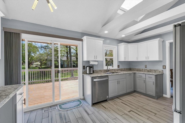 kitchen featuring stainless steel appliances, a sink, light wood-type flooring, white cabinetry, and light stone countertops