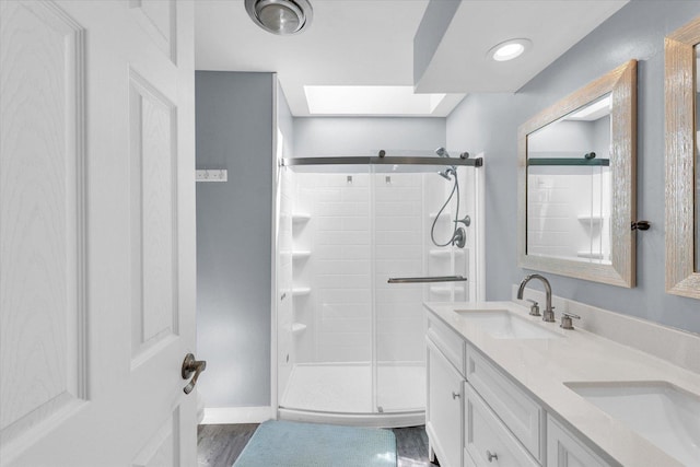 full bath with a stall shower, double vanity, and baseboards