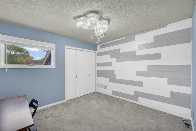 unfurnished office featuring a chandelier, carpet, a textured ceiling, wooden walls, and baseboards