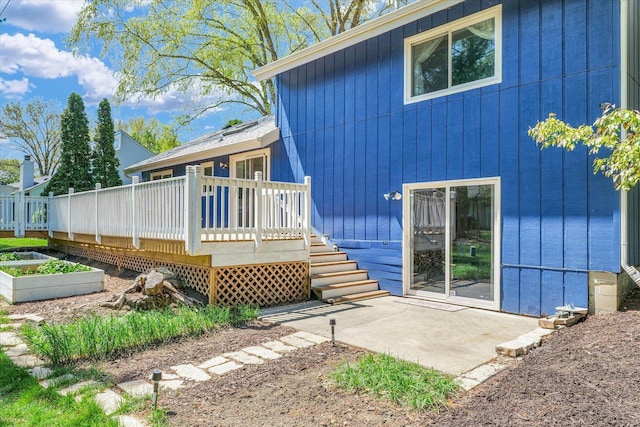 back of property with a deck and a patio