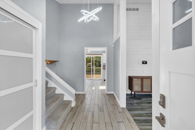 foyer featuring a high ceiling, wood finished floors, a chandelier, baseboards, and stairway