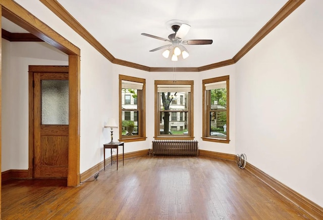 unfurnished room featuring radiator heating unit, baseboards, wood finished floors, and a wealth of natural light
