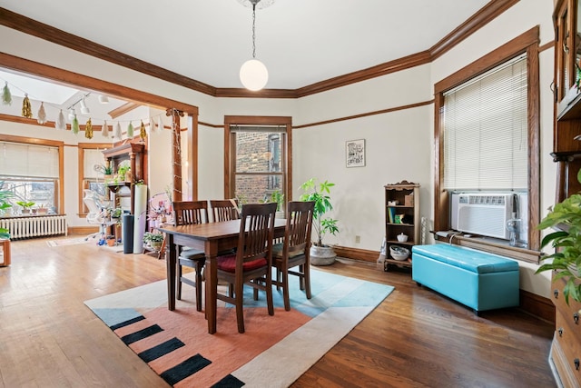 dining space featuring radiator heating unit, wood finished floors, crown molding, and a healthy amount of sunlight
