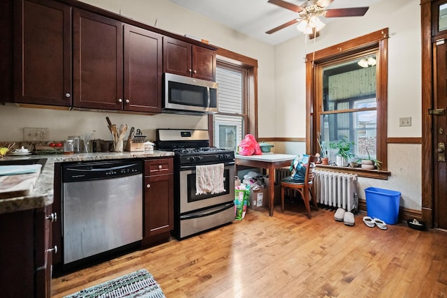 kitchen featuring ceiling fan, dark brown cabinetry, stainless steel appliances, light wood-style flooring, and radiator