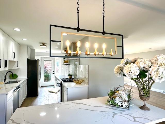 kitchen with a sink, light wood-style floors, appliances with stainless steel finishes, and a kitchen island