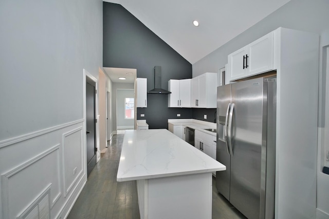 kitchen featuring high vaulted ceiling, wall chimney range hood, light stone counters, stainless steel fridge, and a kitchen island