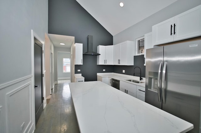 kitchen featuring wall chimney range hood, a sink, light stone countertops, stainless steel refrigerator with ice dispenser, and high vaulted ceiling
