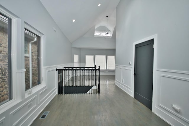 additional living space with visible vents, a wainscoted wall, wood finished floors, and high vaulted ceiling