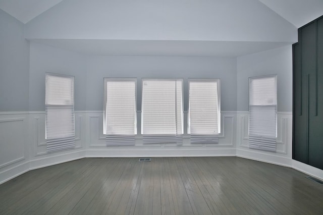 empty room featuring vaulted ceiling, visible vents, and a wainscoted wall