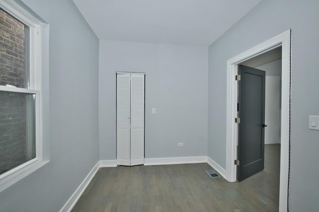 unfurnished bedroom with visible vents, baseboards, and dark wood-style floors