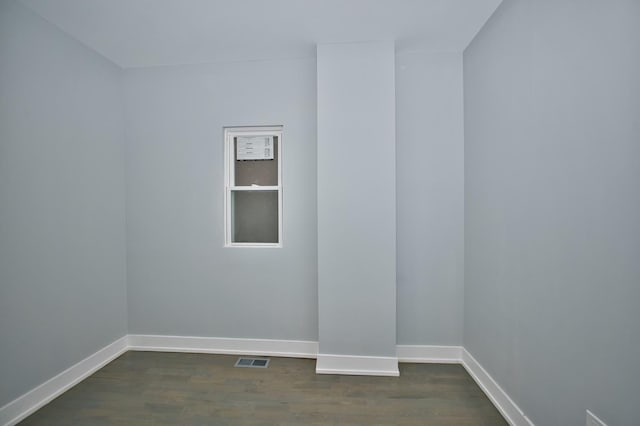 empty room featuring visible vents, baseboards, and dark wood-type flooring