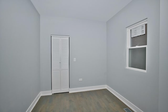 unfurnished room featuring baseboards, dark wood-type flooring, and visible vents