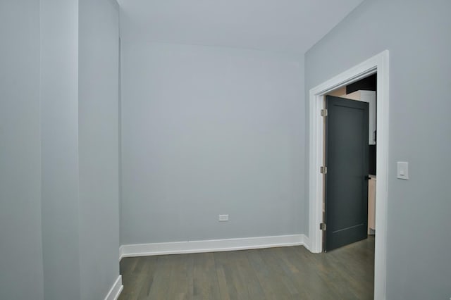 unfurnished room featuring baseboards and dark wood-style flooring