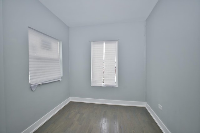 empty room with baseboards and dark wood-type flooring