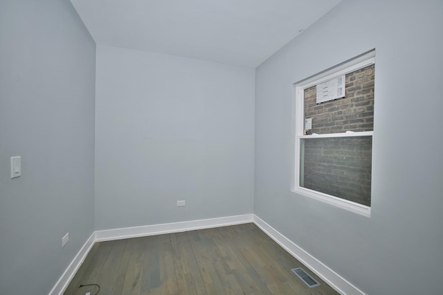 unfurnished room with baseboards, visible vents, and dark wood-style floors