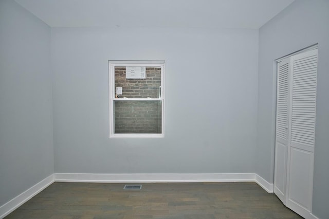 spare room featuring baseboards, dark wood-type flooring, and visible vents