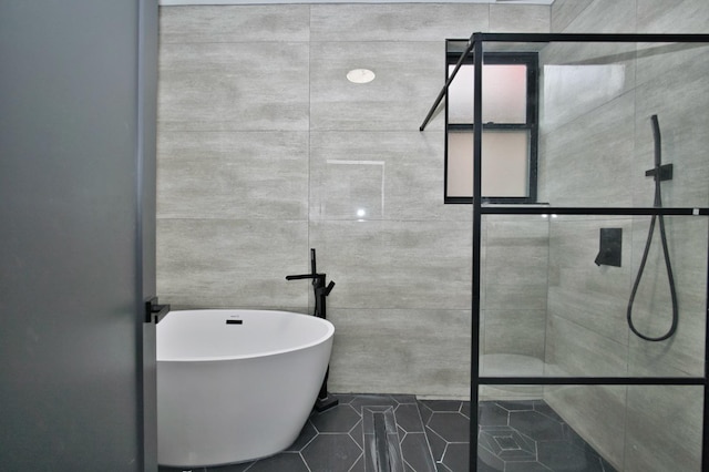 bathroom with a shower stall, a soaking tub, and tile patterned flooring