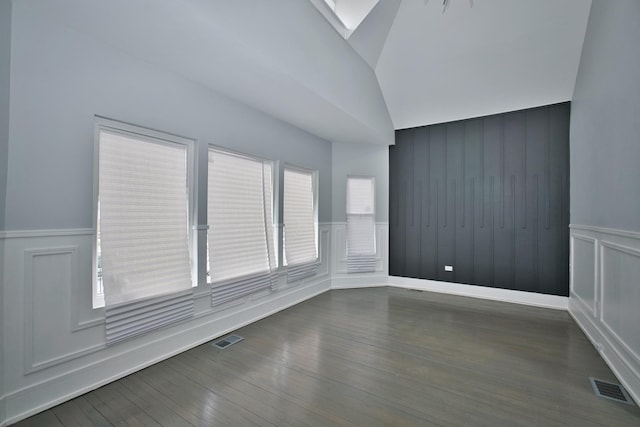 spare room with dark wood-style flooring, a wainscoted wall, visible vents, and a decorative wall