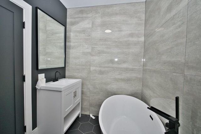 full bathroom with vanity, a freestanding tub, tile patterned floors, and tile walls