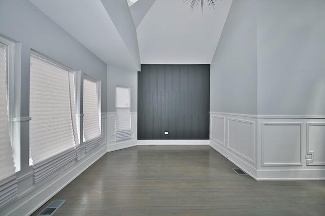spare room with dark wood-type flooring, a decorative wall, a wainscoted wall, and visible vents