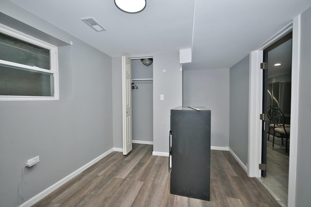 corridor with baseboards, visible vents, and dark wood-type flooring