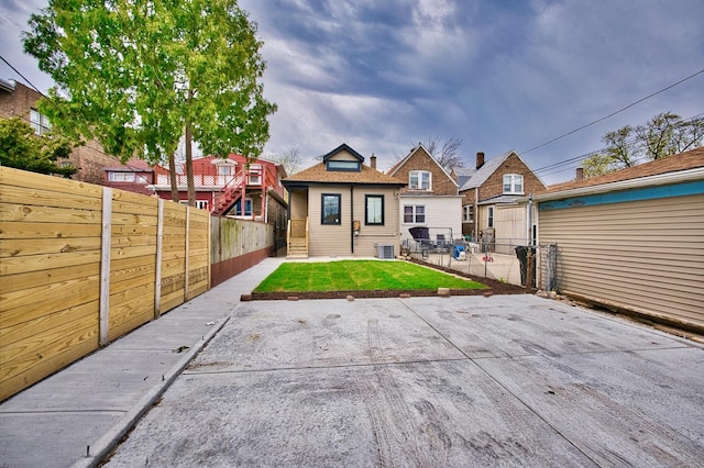 back of house with a patio area, fence private yard, a yard, and central AC