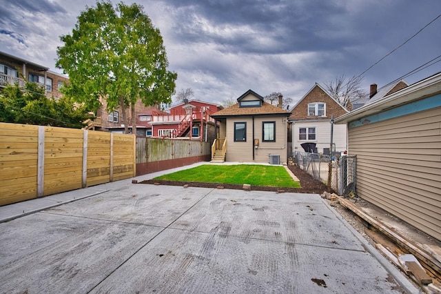 rear view of house featuring fence private yard, a yard, and central air condition unit